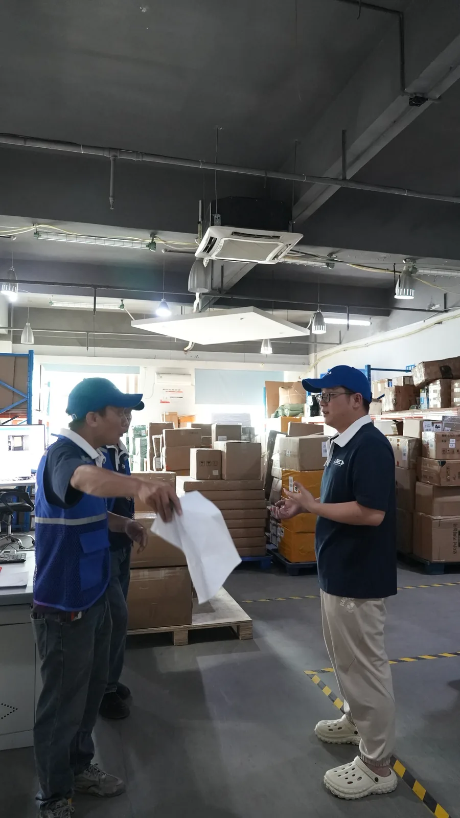 UTEC仓库人员站在待出货货堆旁现场盘点